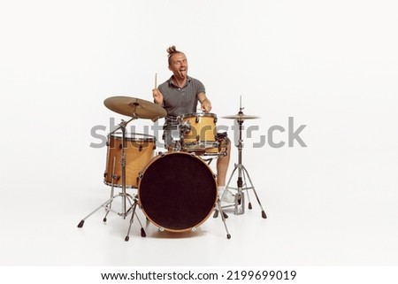 Portrait of funny emotive man playing drums, performing isolated over white background. Bass, rock music. Concept of live music, performance, retro style, creativity, artistic lifestyle Royalty-Free Stock Photo #2199699019