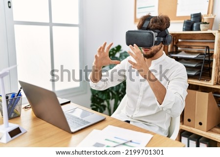 Young arab man using vr goggles working at office