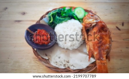 Defocused abstract background of the lunch menu consists of fried tilapia, vegetables and spicy chili sauce.