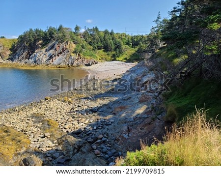 A large cove along a rocky shoreline with cliffs in the distance.