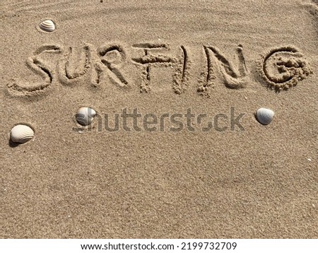 on the beach is carved with letters in the smooth sand the writing Surfing