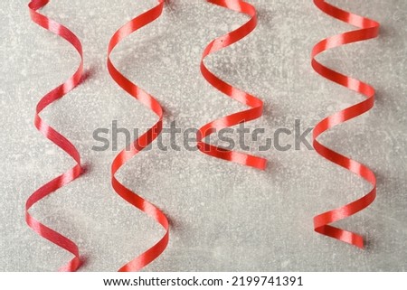 Shiny red serpentine streamers on grey background, flat lay