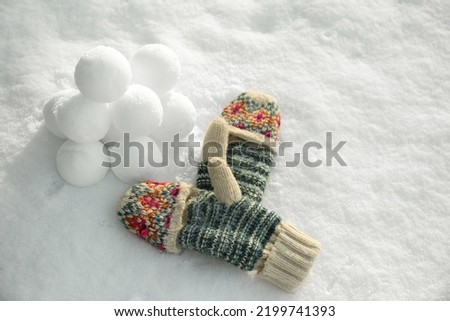 Knitted mittens and snowballs on snow outdoors