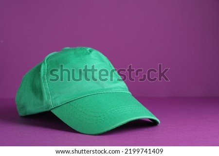 Baseball cap on purple background, space for text