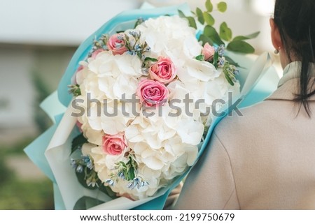 Woman holding flowers big bouquet white hydrangea flowers and pink roses. blooming flowers festive background, pastel and soft bouquet floral card. Mothers day, International Women's Day.