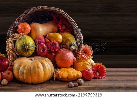 Thanksgiving day still life, background with empty copy space. Pumpkin harvest in wicker basket. Squash, vegetable autumn fruit, apples, and nuts on a wooden table. Halloween decoration fall design.