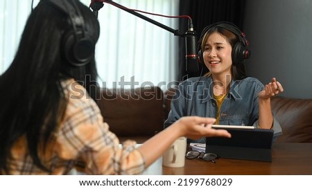Friendly radio host wearing headphone and recording voice over radio interview guest conversation at home studio