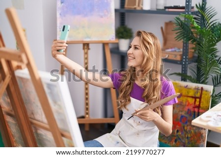Young blonde woman artist smiling confident make selfie by the smartphone at art studio