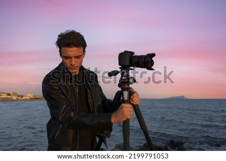 Beautiful Italian man in leather makes photo video on camera for film, elegantly dressed, photographer, outdoor portrait, close up, brutal, tattoo, sunset. people outdoor background. learn photography