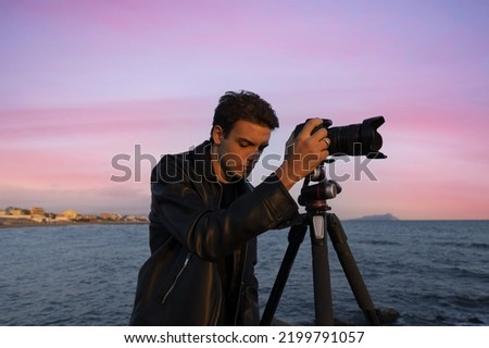 Beautiful Italian man in leather makes photo video on camera for film, elegantly dressed, photographer, outdoor portrait, close up, brutal, tattoo, sunset