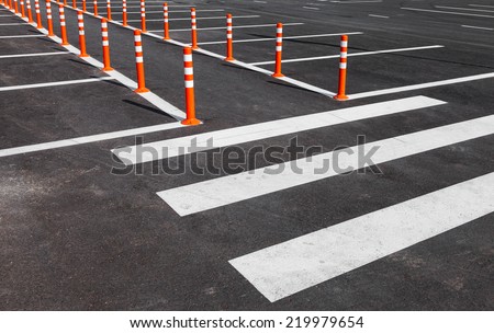 White traffic markings with a pedestrian crossing on a gray asphalt parking lot