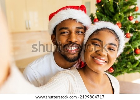 latin hispanic couple taking selfie picture on camera near the christmas tree at home