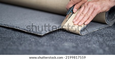Handyman cutting a new carpet with a carpet cutter. Royalty-Free Stock Photo #2199817559