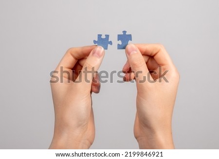 Hands connecting matching jigsaw puzzle pieces. Two details representing companies merging, joint venture, partnership, solution finding. High quality photo