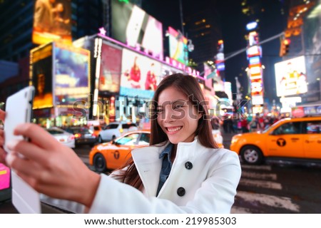 Happy woman tourist taking photo picture with tablet in New York City, Manhattan, Times Square. Girl traveler taking selfie joyful and happy smiling. Multiethnic Asian Caucasian woman in her 20s.