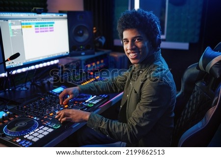 Portrait of radio host using sound mixer in studio Royalty-Free Stock Photo #2199862513