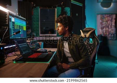 Young man on chair front of monitor in studio of records