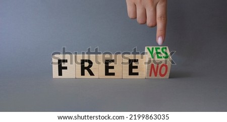 Free symbol. Businessman points at wooden cubes with words Free YES to Free No. Beautiful grey background. Business concept. Copy space