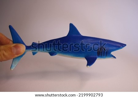 great white plastic toy shark that is being hold from swimming