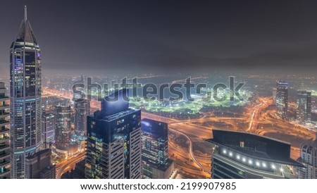 Panorama of Dubai Marina with JLT skyscrapers and golf course night timelapse, Dubai, United Arab Emirates. Aerial view from above towers. City lights illumination