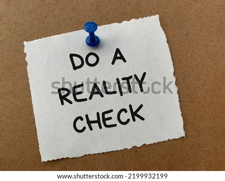 Do a reality check text on white notepad with wooden background. Reality check concept.