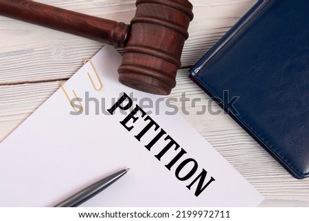 PETITION - word on a white sheet against the background of a judge's gavel, a notebook and a judge's pen. Business concept Royalty-Free Stock Photo #2199972711