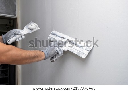 Plasterer applies plaster on the wall during repair and restoration work. Leveling the wall with a spatula.  Royalty-Free Stock Photo #2199978463