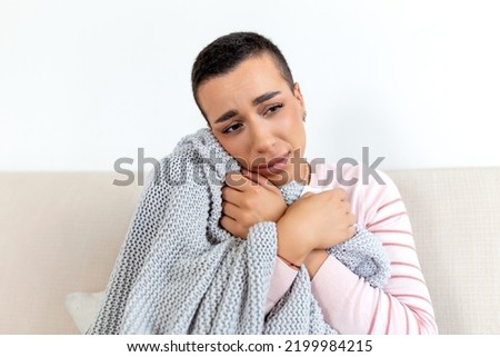 Sick young african woman feeling cold covered with blanket sit on bed, ill black girl shivering freezing warming at home wrapped with plaid, no central heating problem, fever temperature flu concept