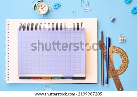 School supplies accessories stationery on blue background, flat lay, top view. Education stuff notebooks, pens, pencils and clock. Back to school concept. Flatlay from above. Copy space