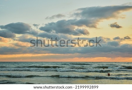 Sunset over the sea with colorful clouds, orange sunlight, autumn sunsets, early autumn, velvet season. The idea of a background or splash screen.