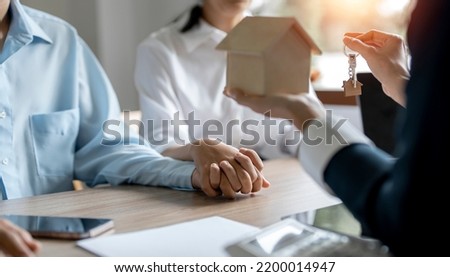 Hands of estate agent giving keys and house model to the couple. The agent handed the keys a young couple. Real estate concept.