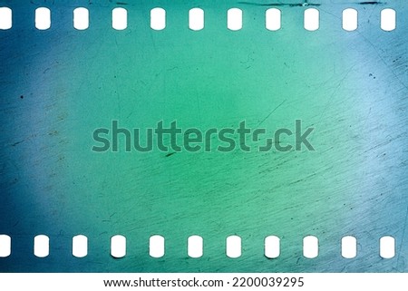 Dusty and grungy 35mm film texture or surface. Perforated scratched camera film isolated on white background. Royalty-Free Stock Photo #2200039295