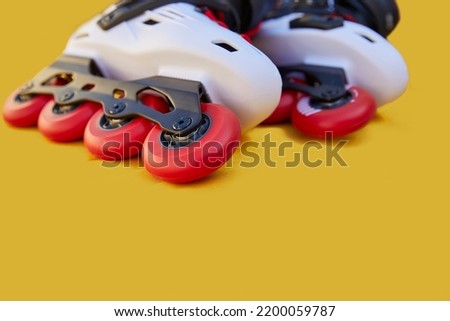 Close-up of inline skate wheels one on top of the other on a yellow background with copyspace