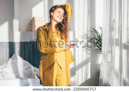 Woman in yellow pajamas hugging pillow and smiling.  Royalty-Free Stock Photo #2200060757