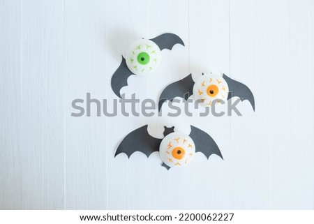 toy eyes with bat wings on a white wooden background, place for text , abstract Halloween concept