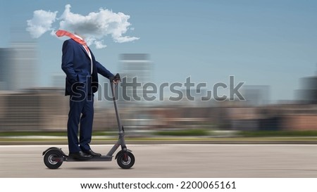 Businessman riding an electric scooter with his head in a cloud: mental fog, distraction and isolation concept, city in the background Royalty-Free Stock Photo #2200065161