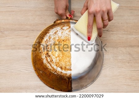 Woman's hand washing only half of a burnt frying pan Royalty-Free Stock Photo #2200097029