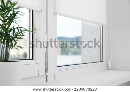 Houseplant on white sill near window with roller blinds Royalty-Free Stock Photo #2200098229