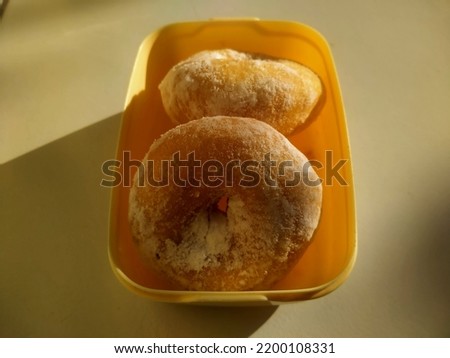 Two donuts coated with powdered sugar