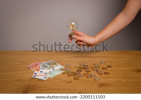 Classic electric light bulb with money scattered on the desk. Photo for Finance and energetic and high electricity bill prices concepts. 
 World economy crisis. 
