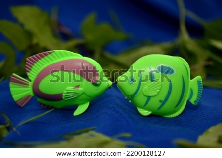 The picture shows green aquarium fish, children's toys, kissing at the bottom of the aquarium.