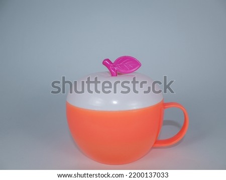 Apple shaped mug made of plastic, orange color, white background