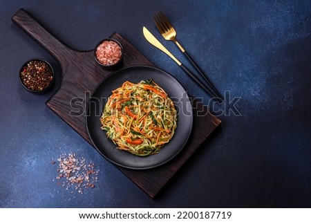 Fresh salad of sliced thin strips of carrot and zucchini on a concrete background. Vegetarian cuisine