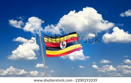 Uganda national flag waving in beautiful clouds.