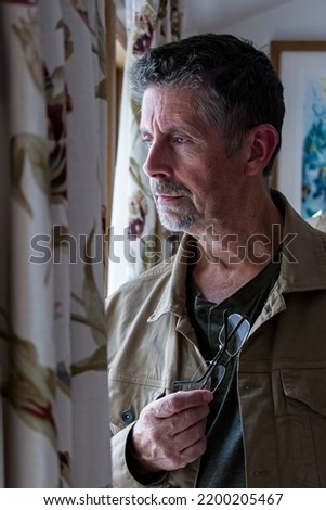




Middle aged man stares out the window. He's pondering, soulfully looking thoughtful. Royalty-Free Stock Photo #2200205467
