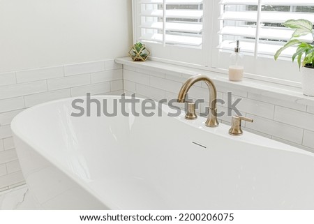 Modern luxury soaking tub with brass faucet interior design staged Royalty-Free Stock Photo #2200206075