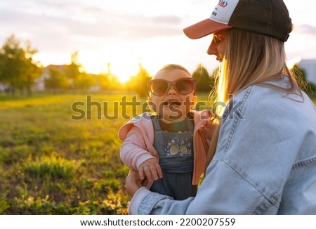 mom, the child is playing in the park, the child is wearing mom's sunglasses