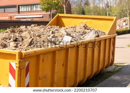 Demolition waste, debris from destruction or renovation of buildings in a yellow container on a work site. Concrete and sand ready to be recycled into new building materials. Circular economy concept Royalty-Free Stock Photo #2200210707