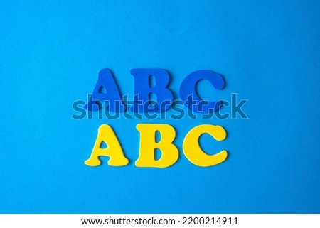 Blue and yellow letters of the alphabet on a blue background. The concept of learning languages