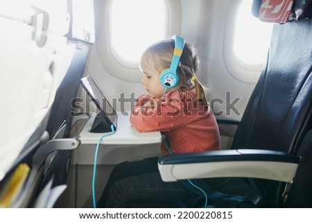 4 year old preschooler girl using tablet while travelling by plane